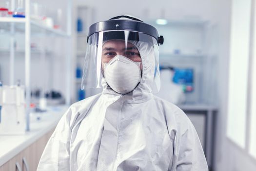 Biochemistry scientist wearing face mask and face shield as safety precaution for covid19 outbreak working in lab. Overworked researcher dressed in protective suit against invection with coronavirus during global epidemic.