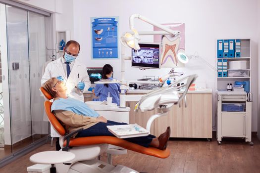 Dentist doing a dental treatment and intervention. on senior woman. Elderly patient during medical examination with dentist in dental office with orange equipment.