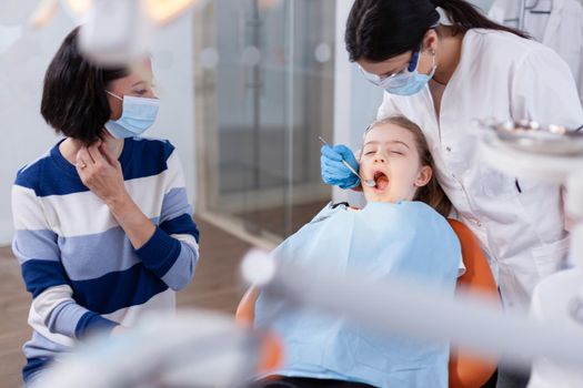 Family visit at dentist office for dental and oral hygine. Dentistry specialist during child cavity consultation in stomatology office using modern technology.