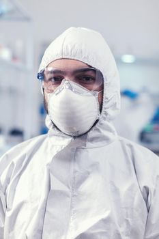 Close up of medicine engineer wearing face mask and suit in laboratory during covid019. Overworked researcher dressed in protective suit against invection with coronavirus during global epidemic.