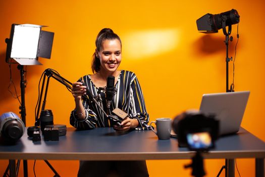 Influencer smiling into camera and recording podcast in studio. Social media star making online internet content about video equipment for web subscribers and distribution, film