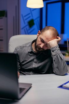 Businessman sleeping in company office due to overworking. Workaholic employee falling asleep because of working late at night alone in the office for important company project.