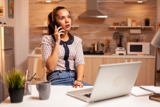 Concentrated businesswoman during phone call late at night from home office. Employee using modern technology at midnight doing overtime for job, business, busy, career, network, lifestyle ,wireless.