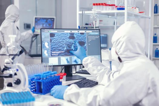 Team of pharmaceutical researchers working in modern laboratory dressed in protection suit. Lab engineers conducting experiment for vaccine development against covid19 virus