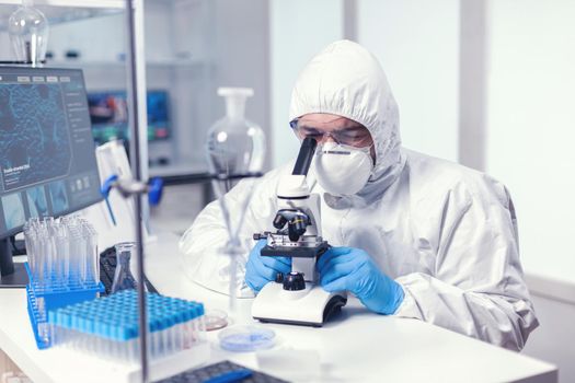 Focused scientist in medicine lab conducting experiment to find a cure for covid19. Virolog in coverall during coronavirus outbreak conducting healthcare scientific analysis.