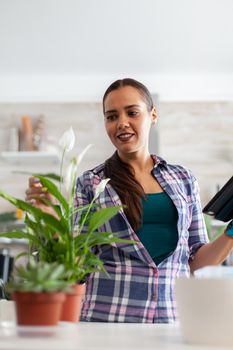Woman checking flowers in home kitchen and using tablet pc. Decorative, plants, growing, lifestyle, design, botanica, dirt, domestic, growh, leaf, hobby, seeding, care, happy, green, natural,