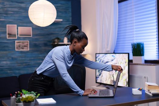 Dark skinned business woman using laptop while working on deadline from home office. Black entrepreneur sitting in personal workplace writing on keyboard.