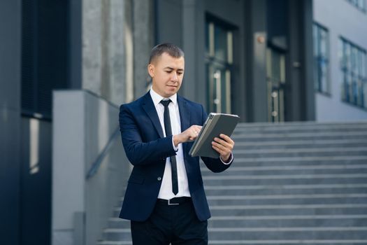 Businessman Working On Tablet Computer Outside Office. Cool businessman using electronic tablet