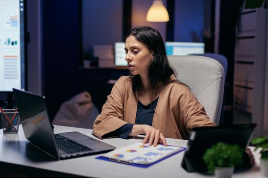 Entrepreneur reading project deadline for important client using tablet pc and laptop. Business woman working overtime at the office to finish a corporate job using tablet pc.