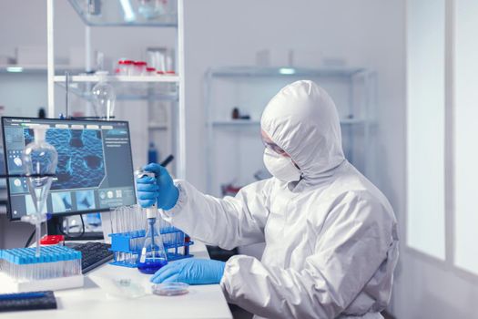 Carefull doctor working with automatic pipette taking sample from test tube. Chemist in modern laboratory doing research using dispenser during global epidemic with covid-19.