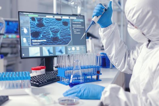 Biochemist man taking sample of liquid holding automatic pipette .Chemist in modern laboratory doing research using dispenser during global epidemic with covid-19.