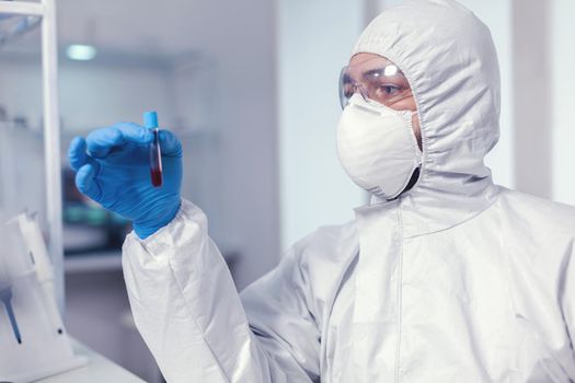 Chemist during coronavirus outbreak working with blood sample dressed in ppe. Doctor working with various bacteria and tissue, pharmaceutical research for antibiotics against covid19.