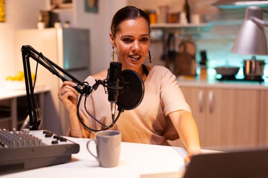 Famous woman holding professional microphone while recording podcast for social media. On-air online production internet broadcast show host streaming live content, recording digital social media.