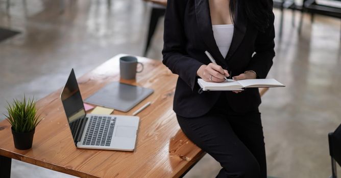 Businesswoman taking note standing in office building.