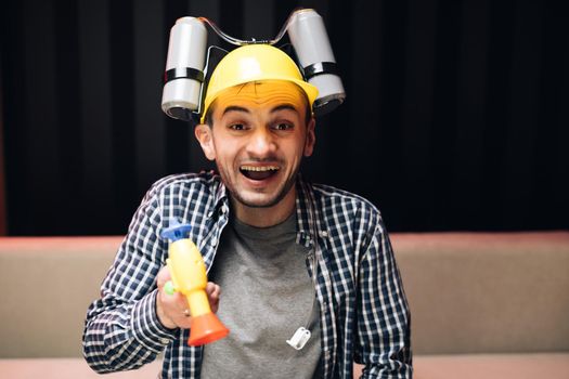 Man sitting on the couch at night in beer helmet and watching TV. Football fan screaming and watching match at home. Screaming and rejoicing.