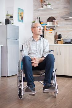 Lonely handicapped pensioner in wheelchair worrying about his life. Elderly handicapped pensioner after injury and rehab, paralysis and disability for depressed invalid full of sorrow, worry and sad face. Retirement period for old people