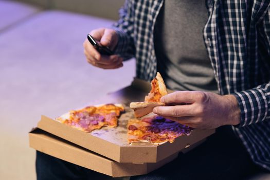 Hot tasty italian pizza from open box, food delivery service at party catering concept. Unrecognizable hand opening carton box with delicious hot pizza. Hand opens a pizza box.