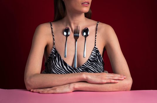 A woman with fork and spoon attached to her chest. Ability stick metal objects body Magnetic people. The concept of human superpowers.