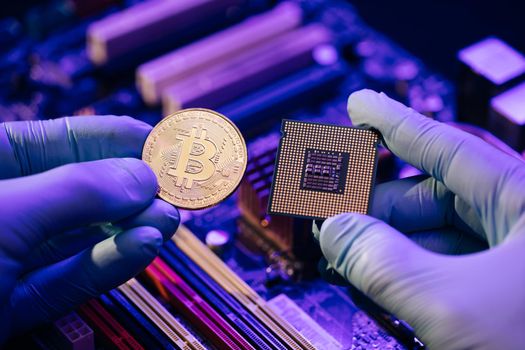 Closeup of Businessman hands hold gold Bitcoin and cpu on motherboard background. Person shows future currency. Mining, trading. Cryptocurrency in the fingers.