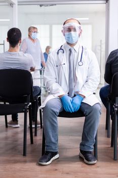 Exhausted doctor in hospital waiting room wearing surgical face mask against coronavirus. Doctor in hospital hallway with medical mask protection epidemic against covid-19. Medical examination room.