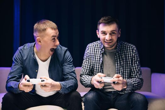 Caucasian men watching tv to play videogame together. Young male friends playing game using joystick at home.
