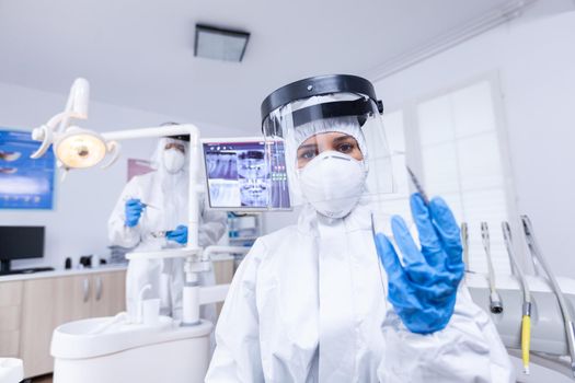 Patient pov of skillful dentist in covid protection treating teeth in dental office. Stomatolog wearing safety gear against coronavirus during heatlhcare check of patient.