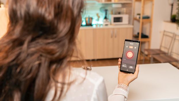 Woman hands holding phone with smart app for home lighting. Person in apartment holding telephone with touchscreen and app for lights.