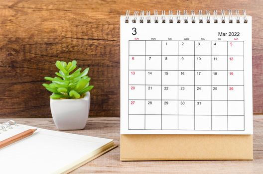 The March 2022 desk calendar on wooden table.