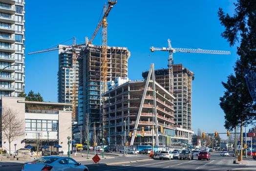 High-rise buildings under construction on bright sunny day. A city street on bright sunny autumn day