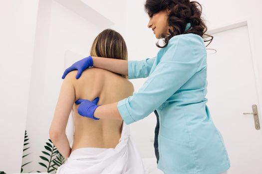 Chiropractor massaging female shoulder on white background. Rehabilitation. Treatment concept. Modern rehabilitation physiotherapy worker with woman client.