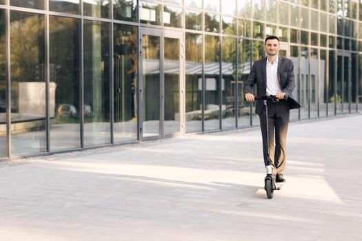 Young businessman riding an electric scooter for a business meeting in the office, office buildings, business man, electric transport, ecological transport, e-skateboard. Eco-friendly transportation.