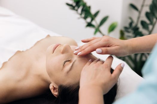 Young caucasian woman getting spa massage treatment at beauty spa salon. Face massage essential oil for skincare, Relaxing massage, Spa skin and body care.