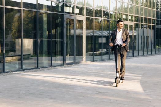 Handsome man in a suit riding electric scooter in a city. Adult businessman riding with electric scooter to work. Man rides an electric scooter on the road. Modern way of getting around.