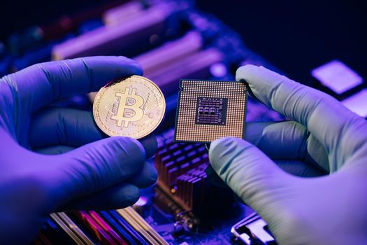 Man hands hold gold Bitcoin and cpu on motherboard background. Person shows future currency. Mining, trading. Cryptocurrency in the fingers.