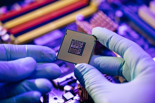 Laboratory technician holds a powerful processor in his hands. CPU computer processor shallow focus. CPU socket of the computer's motherboard. Concept of computer, motherboard, hardware and technology