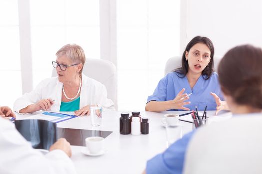 Medical team sitting and discussing about patient diagnosis in conference room. Clinic expert therapist talking with colleagues about disease, medicine professional