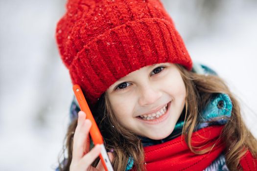 Close up of young beautiful woman in winter hat talking emotionally and surprised talking on cell phone