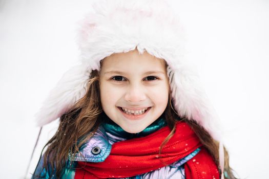 Portrait Little Child Girl Smiling Looking at Camera Standing on Street in City on Winter Day. Concept of a happy childhood. Preschool child in winter outfits with pretty face