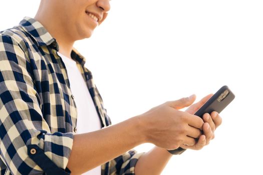 Caucasian hipster man in shirt is using a smartphone on a street in downtown. He smiles and looks successful. He's browsing the web on his device.