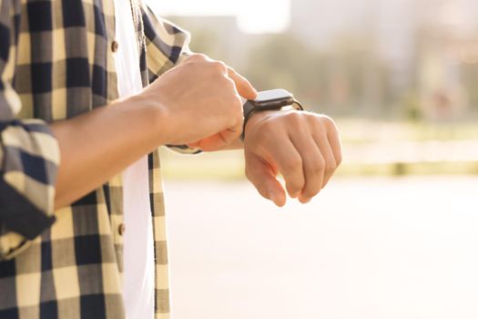 Smart watch. Smart watch on a man's hand outdoor. Man's hand touching a smart watch. Close - up shot of male's hand uses of wearable smart watch at outdoor