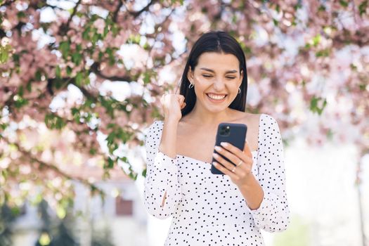 Portrait of happy woman enjoy success on mobile phone. Closeup joyful girl reading good news on phone. Surprised lady celebrating victory on phone.