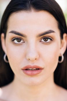 Attractive young lady with her hair blowing in the wind. Beautiful face of tender attractive woman staying outside. Perfect model with creative vivid makeup and pink lipstick on lips. Ethnicity.