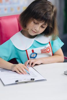 Close up wrinkled female writing information in medical registration journal. Funny little girl doctor therapist working at office, handwriting notes.