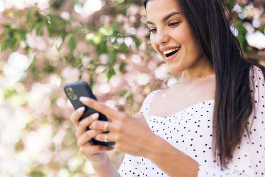 Closeup joyful girl reading good news on phone. Surprised lady celebrating victory on phone. Portrait of happy woman enjoy success on mobile phone.