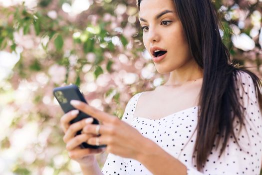 Surprised lady celebrating victory on phone. Portrait of happy woman enjoy success on mobile phone. Closeup joyful girl reading good news on phone.