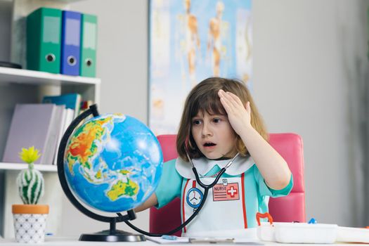 Ecology and global warming concept. Earth Temperature with Thermometer Icon for Global Warming and Climate Change. Little kid girl dressed in a doctor's suit measures the temperature of the Earth.