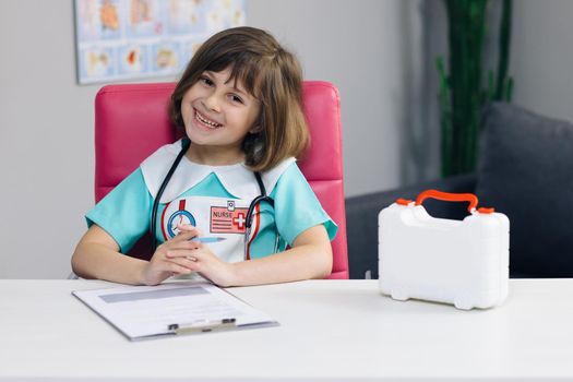 Portrait shot of Female medical nurse in medic uniform looking at camera and smile. Cute adorable little preschool kid girl smiling in hospital.