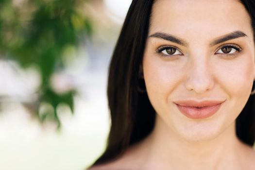 Face of beautiful soft woman with natural make-up looking at camera. Portrait young asian pretty brunette girl outside at sunshine. Etnnicity. People. Beauty.