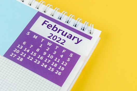 The February 2022 desk calendar on yellow background.