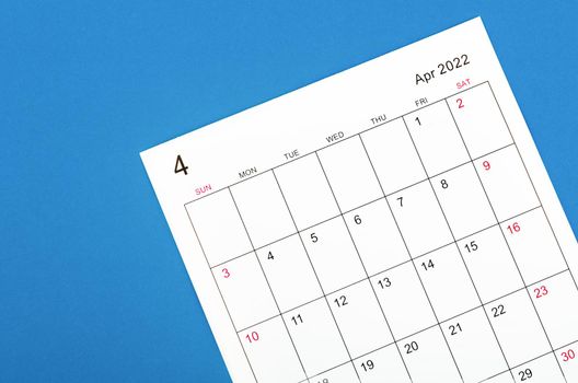 Close up April 2022 calendar sheet on blue background.